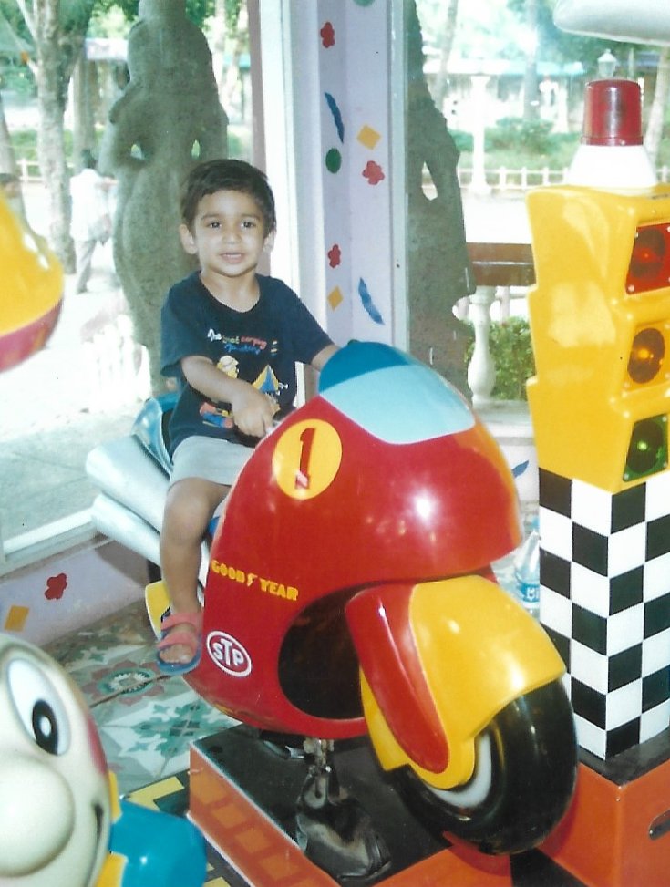 Satvik as a toddler on a red toy motorbike ride